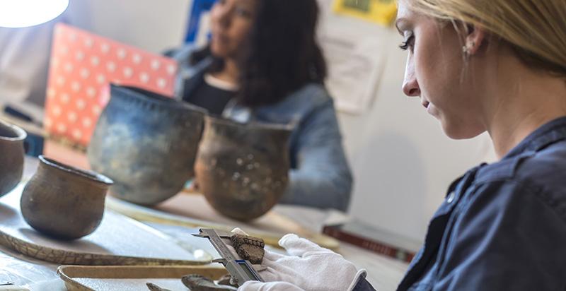 student and professor studying artifacts